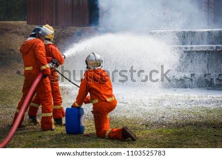 Firefighters extinguish the fire with a chemical foam coming from the fire engine through a long hose, Fire Brigade dispense snow white foam 
