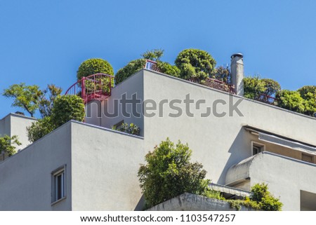 Stone house with bushy trees. White smooth walls decorated with natural green plants. Cities and urban life concept photo