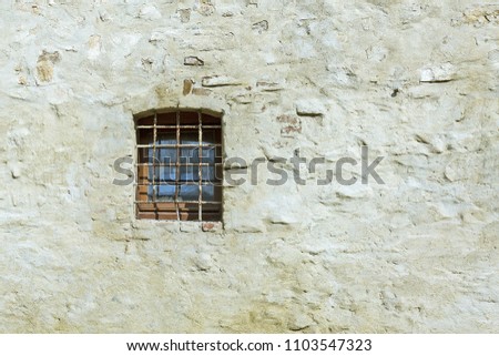 Thick barred window in old stone wall. Within light brown brick wall with various cement patches. Texture design concept photo