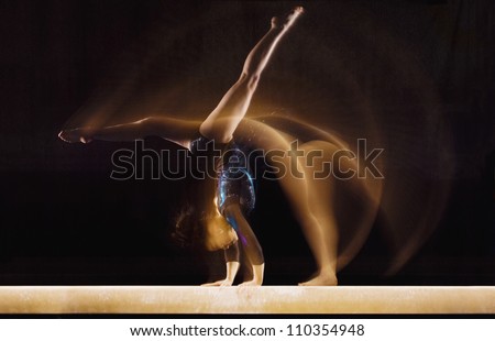 Female gymnast in motion on balance beam