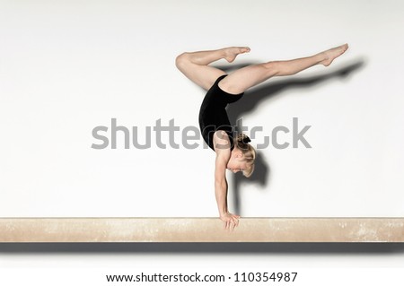 Young female doing a handstand on balance beam Royalty-Free Stock Photo #110354987