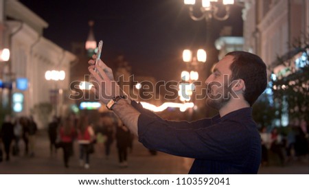 Tourist man taking photo in with smartphone at night city