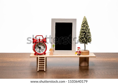 Blank black photo frame with Santa and Angel with Christmas tree and red alarm clock
