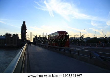 Sunset image of the silhouette of big ben during a golden sunset with traffic and london busses driving on the right side of the bridge.  Big ben is covered with scaffolding. April 2018.