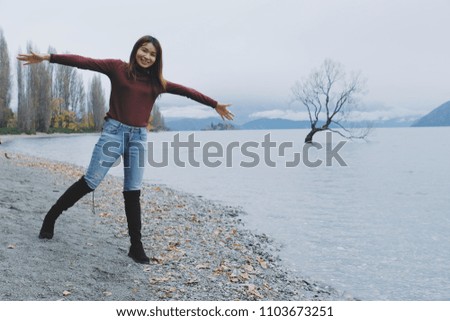 Beautiful woman smile and happy at wanaka tree the lonely tree at wanaka lake at New Zealand