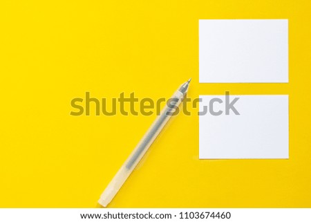 Two papers and a pen on yellow background