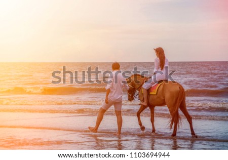 Honeymoon romantic couple in love holding hands and riding horse with on beautiful sky at beach .Lovers or newlywed married young couple by the sea. Wedding in Thailand