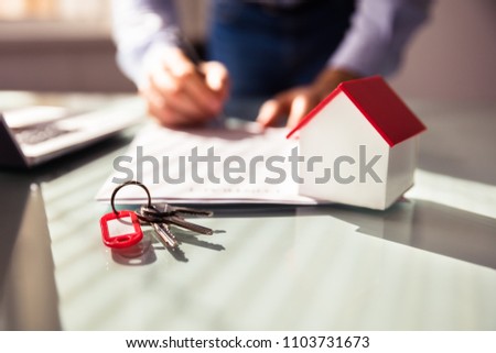 Close-up Of House Model And Key Near Human Hand Signing Contract