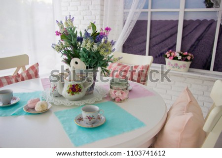 Table setting. Tea drinking. Interior in light colors. Feast. White table. Blue wipes. Zefrm on the plate. Cups for tea. Fresh flowers in a vase.