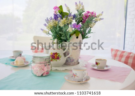 Table setting. Tea drinking. Interior in light colors. Feast. White table. Blue wipes. Zefrm on the plate. Cups for tea. Fresh flowers in a vase.