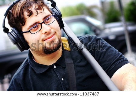 A boom operator wearing headphones and holding his boom.