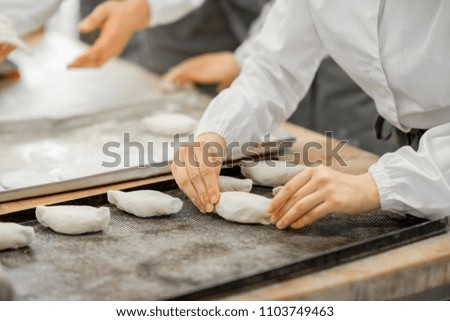 Worker forming raw buns with filling for baking at the manufacturing