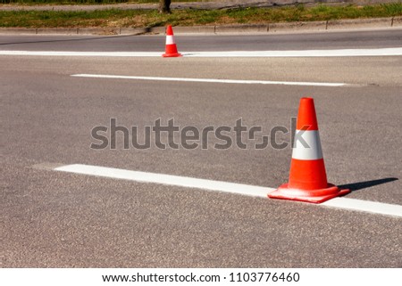 Work on road. Construction cones. Traffic cone, with white and orange stripes on asphalt. Street and traffic signs for signaling. Road maintenance, under construction sign and traffic cones on road.