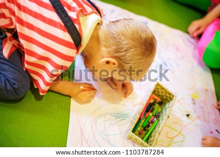 a child draws with crayons on paper