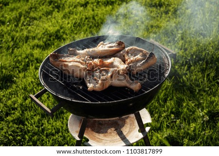 Grilling chicken legs soutside on barbucue in a summer day. Much smoke come out.