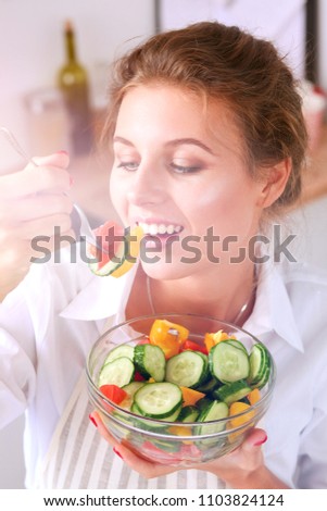 Smiling young woman preparing salad in the kitchen.
