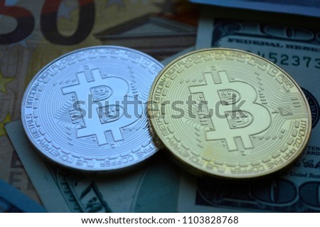 Two Bitcoin coins lie on the background of currency bills