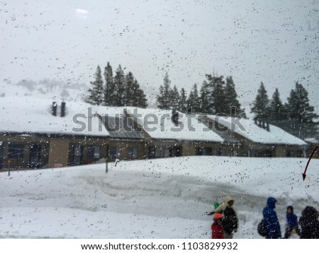 Blurry picture of houses in the winter and people walking by. Picture through a window on a rainy day. 
