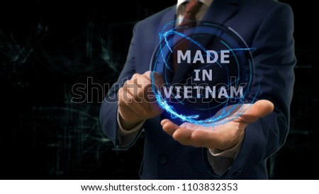 Businessman shows concept hologram Made in Vietnam on his hand. Man in business suit with future technology screen and modern cosmic background