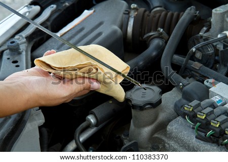 Auto mechanic checking oil Royalty-Free Stock Photo #110383370