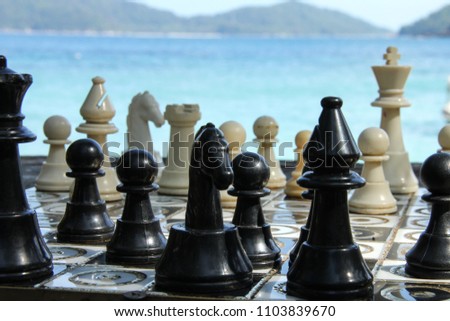 Close-up of chess game pieces on a board with a blue beach/sea background taken in the day in Malaysia, Asia. 