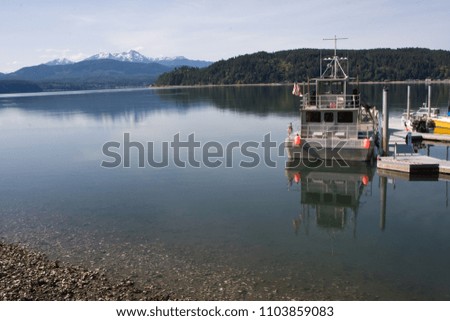 Horizontal Photo of the Hood Canal in Washington State with Olympic Mountains in background and docked boat reflection