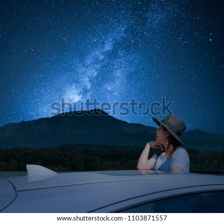 Asian women tourist standing in a sunroof car watching the sky and the Milky Way at night