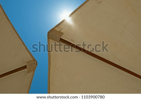 two white umbrella close-up on a bright blue sky background