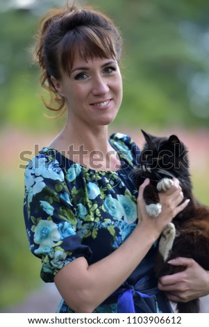 brunette in summer with a black cat in her arms