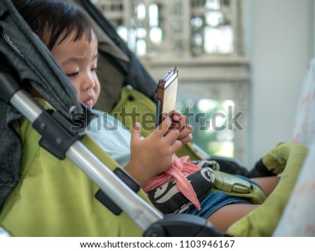Kid girl playing smartphone lying on stroller