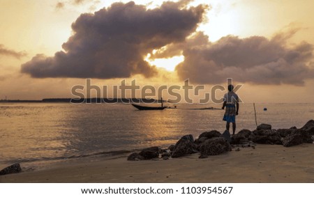 Fisherman watches a fishing boat at sea near Digha rural beach at sunrise.