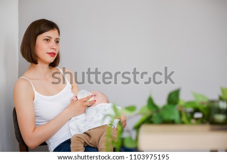 Photo of happy mother feeding her son with milk from bottle