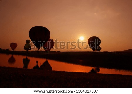 Sunset sky background balloon picture. Silhouette of people with hot air balloon in the background at sunrise