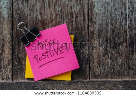 Motivational think positive slogan Note pads and paper clip on Old wood background Royalty-Free Stock Photo #1104039305