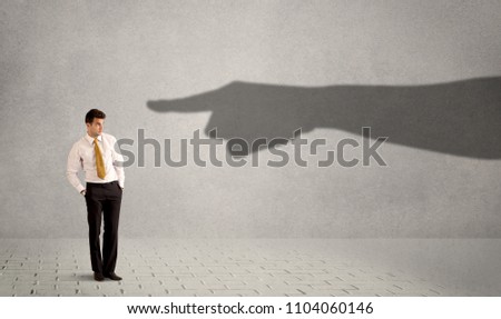 Business person looking at huge shadow hand pointing at him concept on background Royalty-Free Stock Photo #1104060146