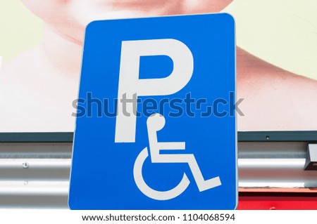 Blue parking sign  for disabled persons in grocery stores parking lot.