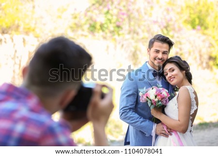 Professional photographer taking photo of wedding couple, outdoors