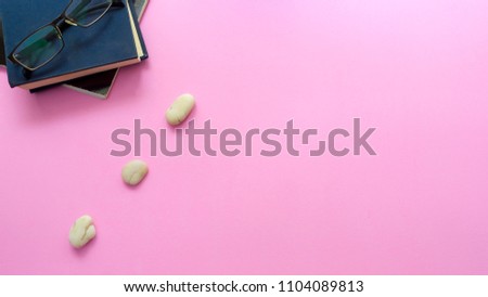 Balance concept between of Zen and work present by setting a natural zen rock stone stack, Surrounded with notebook and glasses, top view on pink background