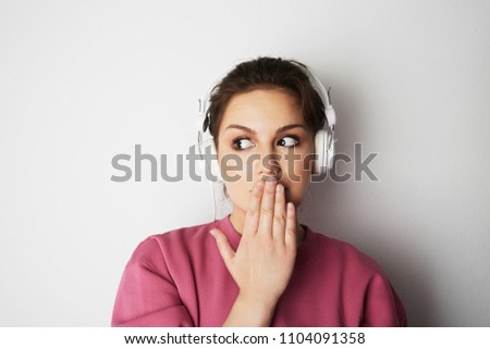 Fashion pretty cool girl in white headphones listening to music wearing colorful pink hoody over white background
