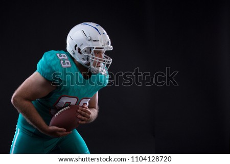 Portrait of American football player holding a ball in both his arms. Copy space. Rugby