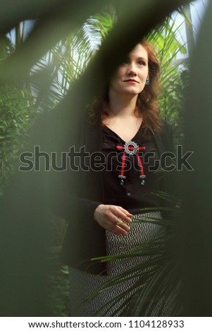 Young woman in jungle. Photo taken through leaves. 