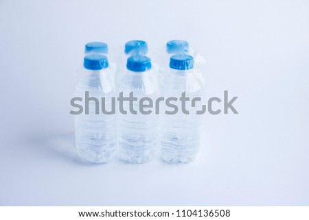 Six small pet bottles of natural spring water in transparent packing 