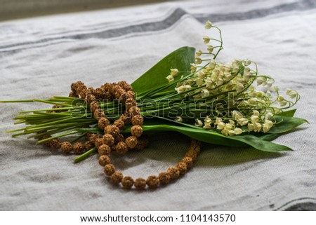 Sihivaism rudraksha with white flowers isolated on craft natural linen. Cult religion objects for praying and mantra reading. Worship of God. 