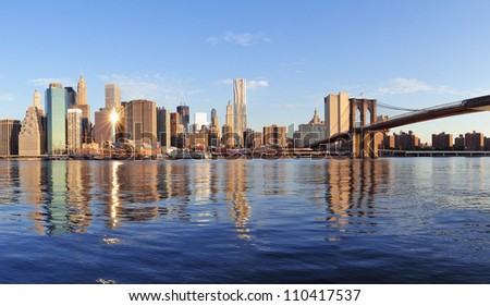 Brooklyn Bridge with lower Manhattan skyline panorama in the morning with cloud and river reflection over East River in New York City