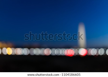 Abstract Tall high Washington Monument memorial in blue sky at evening night in winter, lawn, illuminated bright lights dark in December bokeh background