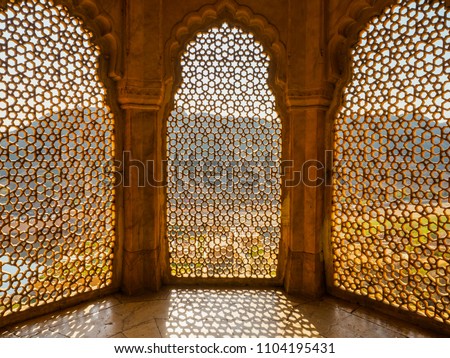 Perforated wall in the building of the palace in the Amber Fort, Jaipur, Rajasthan State. Royalty-Free Stock Photo #1104195431
