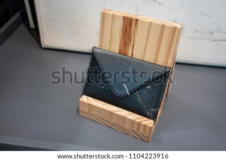 Black leather wallet on wooden stand for display on grey shelve