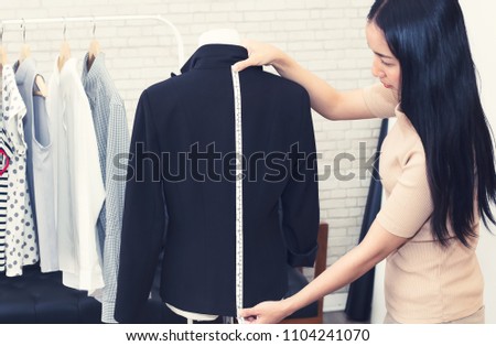 Fashion designer measuring a dress. Shallow depth of field.
Young woman choosing clothes and measure clothes on a puppets