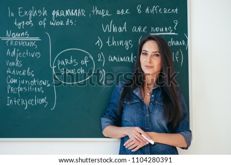 Portrait of female english teacher in front of blackboard. Royalty-Free Stock Photo #1104280391