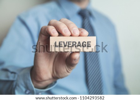 Businessman showing Leverage word in wooden block. Royalty-Free Stock Photo #1104293582